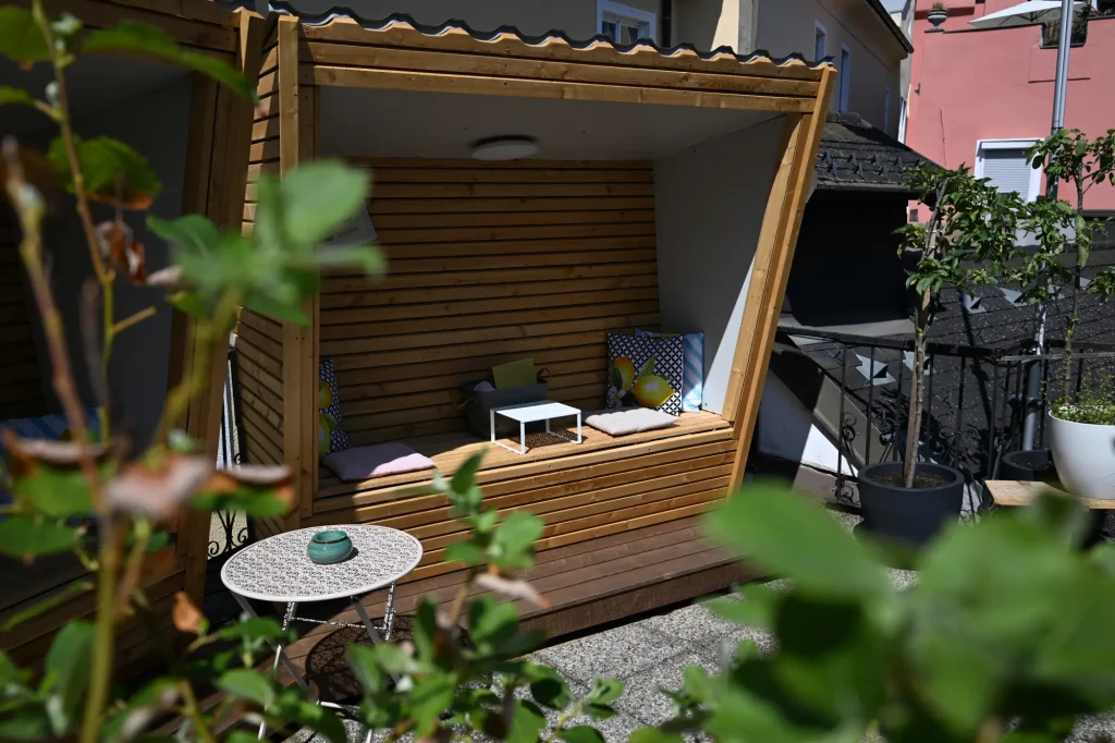 Gemütliche Holz-Sitzecke auf Terrasse mit Kissen und Pflanzen